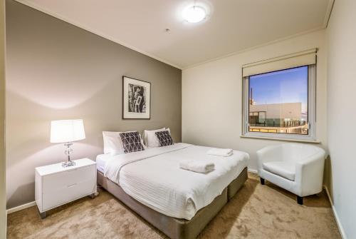 墨尔本百夫长独家住宿公寓的卧室配有床、椅子和窗户。