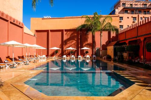 马拉喀什戴文酒店＆马拉喀什Spa的一座带椅子和遮阳伞的游泳池位于一座建筑旁边