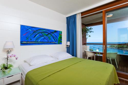 罗维尼Maistra Select All Suite Island Hotel Istra的一间卧室设有一张绿色的床和一个大窗户