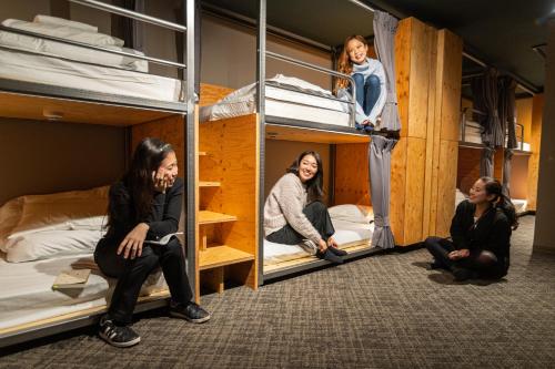 东京Wise Owl Hostels River Tokyo的三名妇女坐在双层床上