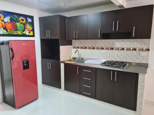 佩雷拉Linda y acogedora casa的厨房配有红色冰箱和黑色橱柜