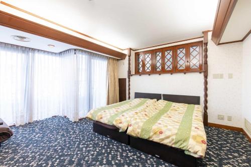 东京ふたばホテル的一间卧室设有一张床和一个大窗户