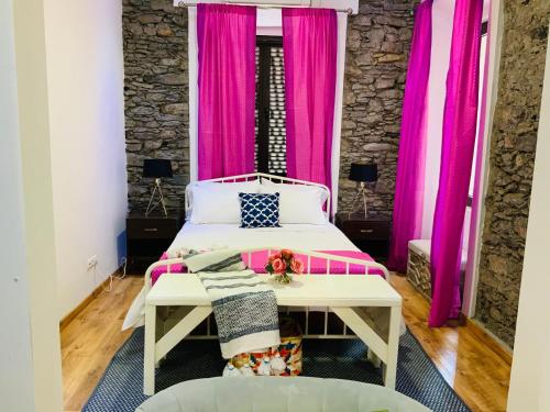 普拉亚Techas City Center Luxurious Suite的卧室配有粉红色窗帘和床