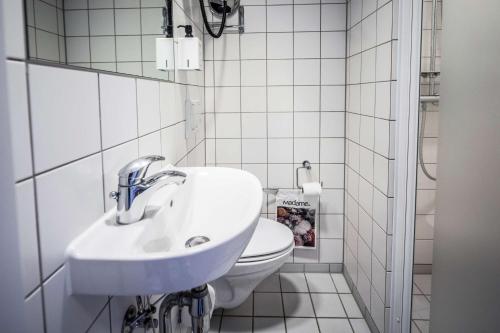奥胡斯斯堪的克马约尔酒店的白色的浴室设有水槽和卫生间。