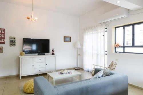拉马特甘Judith's Place - Stylish Apartments的客厅配有蓝色的沙发和电视