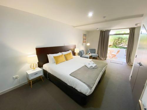 皇后镇Tekau A charming, quiet and spacious studio的卧室配有一张带黄色枕头的大型白色床。