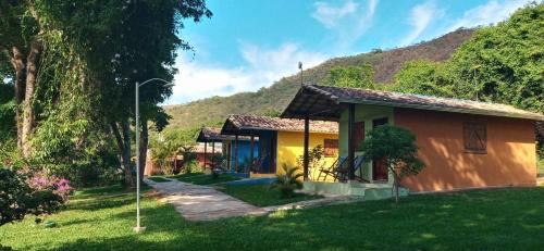 西波山Chalés Jardim da Serra的一座小黄色房子,后面有一座小山