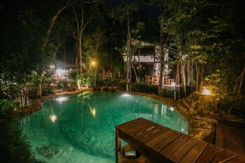 图卢姆Nahouse Jungle Lodges的夜间游泳池,设有木凳