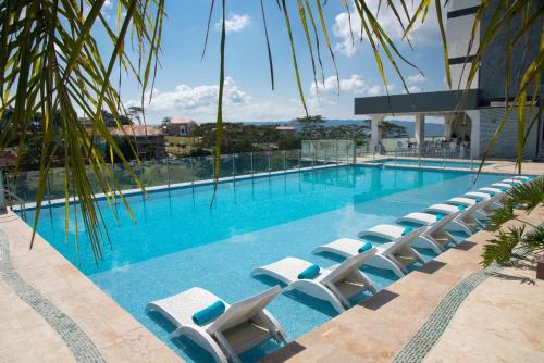 布卡拉曼加Punta Diamante Premium Hotel的大楼前带躺椅的大型游泳池