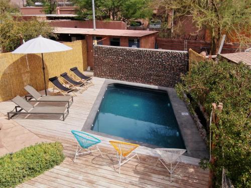 圣佩德罗·德·阿塔卡马Hotel Jardin Atacama的一个带椅子和遮阳伞的游泳池