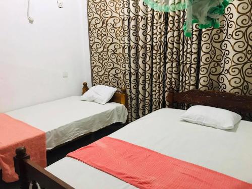 TanamalwilaTharuka Rest Inn Hotel的带两张床和窗帘的房间