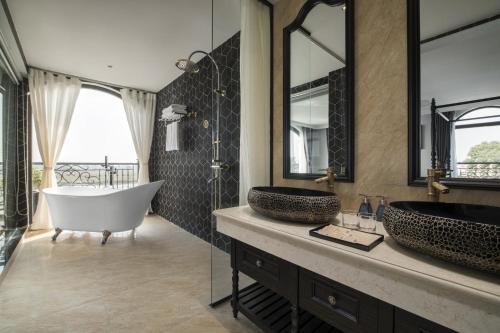宁平Lalita Boutique Hotel & Spa Ninh Binh的浴室设有2个水槽、浴缸和镜子