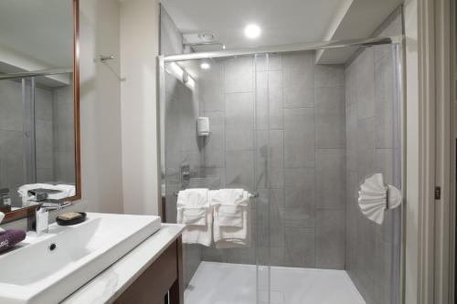 普莱西德湖Lake Placid Inn Boutique Hotel的带淋浴和白色盥洗盆的浴室