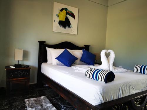萨玛拉Tuki Tuki Lodge的一张带蓝色和白色枕头的床和天鹅