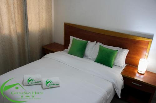 马普托Green Stay house的卧室配有带绿色枕头的白色床
