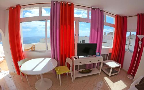 大塔拉哈尔Apartamento junto el mar的一间设有红色窗帘和一张书桌及电视的房间