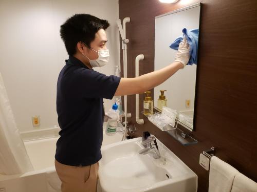 YoshidaSmile Hotel Shizuoka Yoshida Inter的戴面具的人在浴室里擦镜子