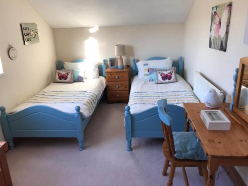 Llansaint布阿斯Y度假屋的一间卧室设有两张床和一张木桌