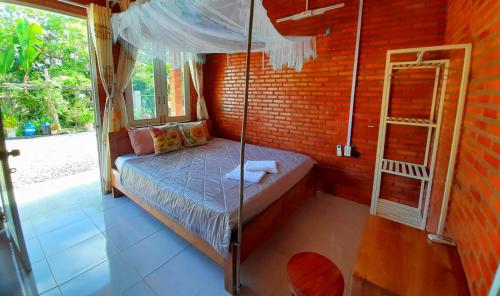 吉仙Cat Tien Backpackers Hostel的卧室配有一张位于砖墙的天蓬床