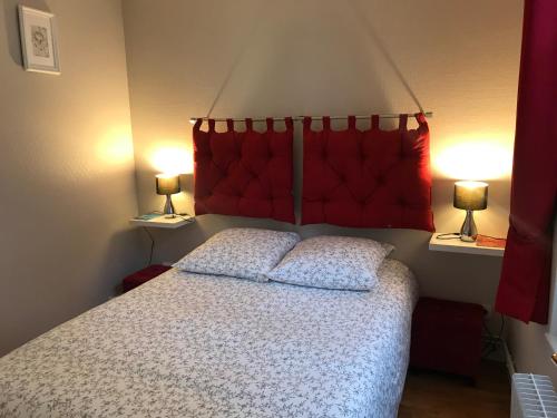 翁弗勒尔Les logettes的一间卧室配有一张带红色床头板的床和两盏灯。
