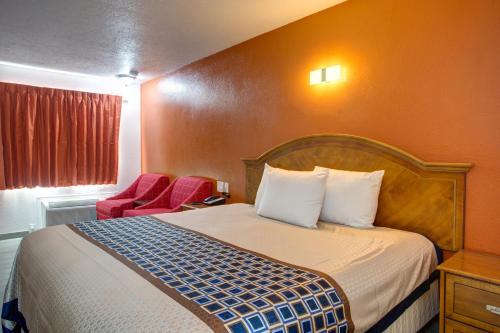 布兰森Motel 6 Branson, Mo的酒店客房,配有一张床和一张红色椅子