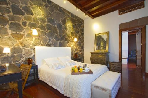 蒂亚斯卡萨卢拉英雄度假屋的一间卧室设有一张床和石墙