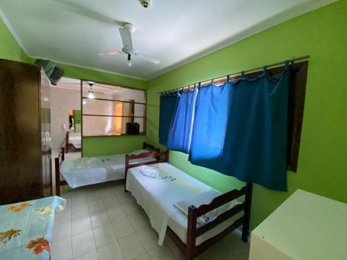 瓜鲁雅卡萨多月酒店的配有两张床铺的客房,拥有绿色的墙壁和蓝色的窗帘