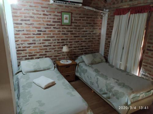科隆Cabañas Rincón del Río的一间卧室设有两张床和砖墙
