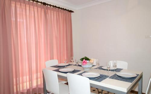 凯阿玛Kiama Coastal Escape的一间设有白色桌子和白色椅子的用餐室