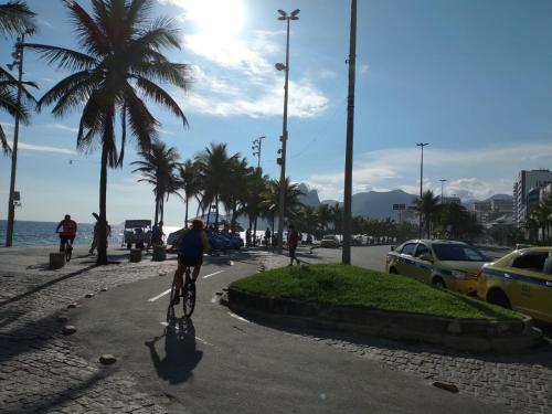 里约热内卢Arpoador Premium Suítes的骑着自行车在海边人行道上的人