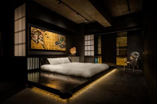 东京艺术家酒店 - 秋叶原BnA一室公寓的卧室配有一张大床,墙上挂有绘画作品
