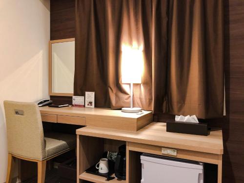 广岛KOKO HOTEL Hiroshima Ekimae的一张桌子,里面配有一盏灯和一把椅子