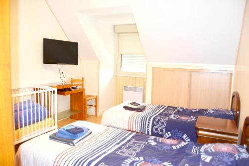 PlomelinMaison de 2 chambres avec jardin clos et wifi a Plomelin的一间卧室配有两张床和一张婴儿床。