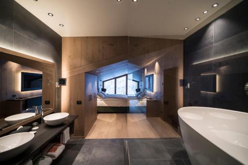 科尔福索Hotel Cappella的一间带两个盥洗盆和浴缸的浴室以及一间卧室