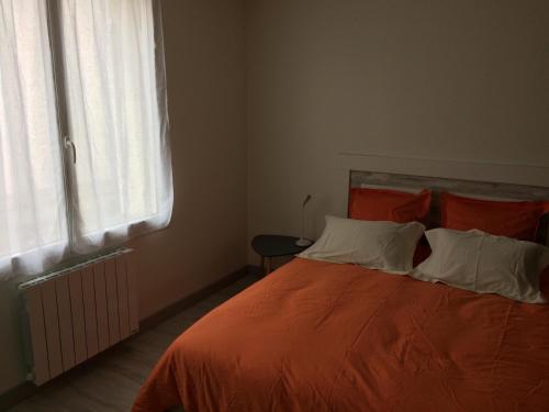 桑特La parenthèse的一间卧室配有带橙色床单的床和窗户。