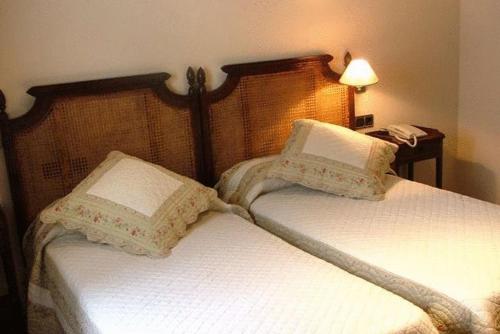 OrceraHostal Rural La Montería的一间卧室配有两张带白色床单和枕头的床。