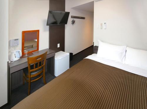 铃鹿市Hotel Trend Suzuka的配有一张床和一张书桌的酒店客房