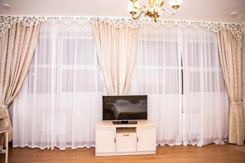 阿德勒自由飞翔酒店的客厅配有白色窗帘和电视