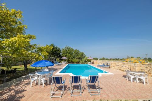 梅利萨诺Villa Lotus的游泳池配有椅子、桌子和遮阳伞