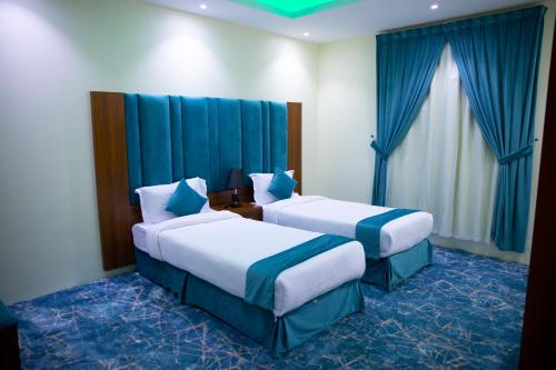 哈费尔巴廷فندق بــــاســــيل的两张位于酒店客房的床,配有蓝色窗帘