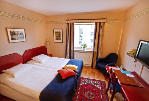 哥德堡奥基迪酒店的一间卧室配有一张床、一张书桌和一台电视
