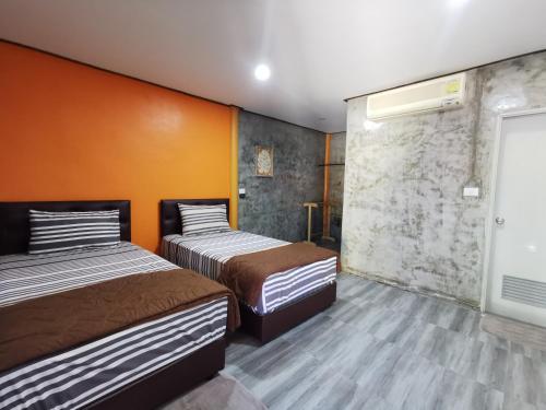 春武里Viman Resort的橙色墙壁客房的两张床