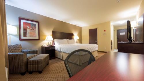 坎卢普斯假日套房酒店-坎卢普斯的酒店客房带一张床、一张桌子和椅子
