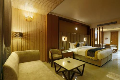 古尔冈Hotel Omega - Gurgaon Central的酒店客房配有床、沙发和桌子。