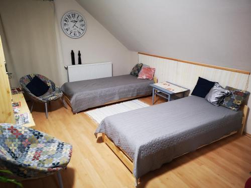 考波什堡Ágnes Apartman的一间设有两张床的客房和墙上的时钟