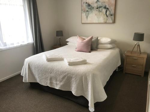 罗托鲁瓦Rose Apartments Central Rotorua- Accommodation & Private Spa的卧室配有白色的床和2条毛巾