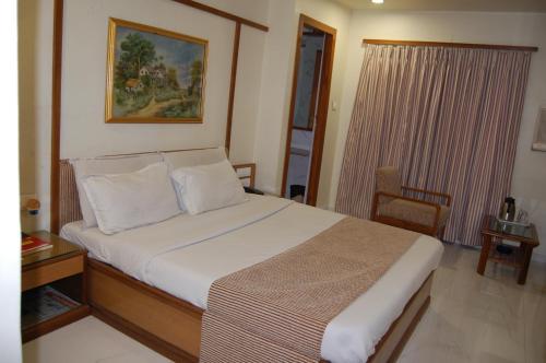 艾哈迈达巴德Hotel Vice President的一间卧室配有一张床、一张桌子和一个窗户。