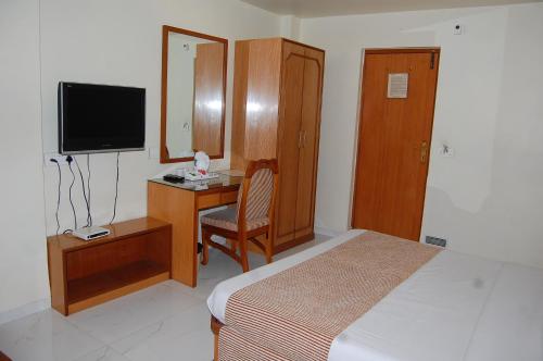艾哈迈达巴德Hotel Vice President的一间卧室配有一张床和一张书桌及电视