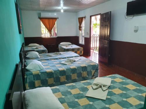 拉利伯塔德Papaya Lodge的一间设有三张床和一台电视的房间