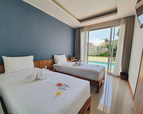库塔RakaAyu Kuta的酒店客房设有两张床和窗户。